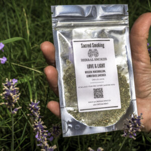 hand holding a pouch of loose herbs in a bush of lavender